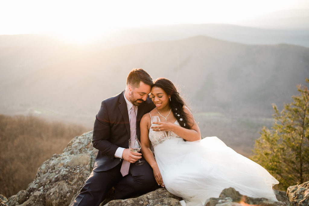 A couple drinks champagne at the top of the mountain after their elopement