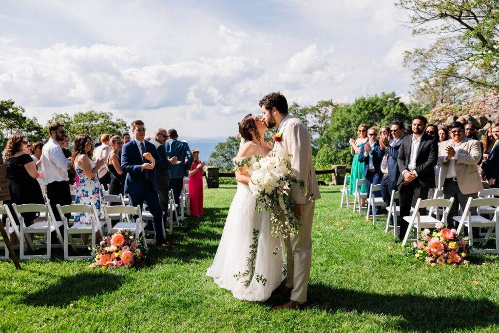 A couple kisses as they walk back down the aisle at Skyland Resort -- one of the best intimate wedding venues near Charlottesville, Virginia. 