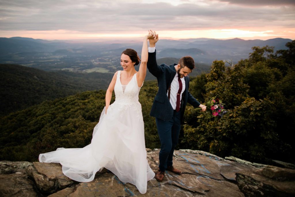 A couple holds hands in the air as they celebrate their elopement in the Blue Ridge Mountains