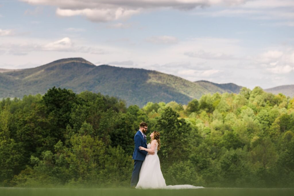 A couple in wedding attire embraces in front of mountain views at House Mountain Inn