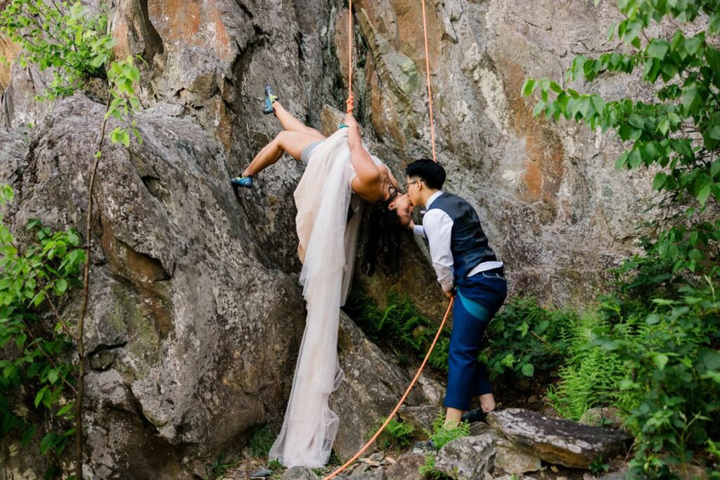 A couple kisses while rock climbing during their adventurous elopement in Virginia