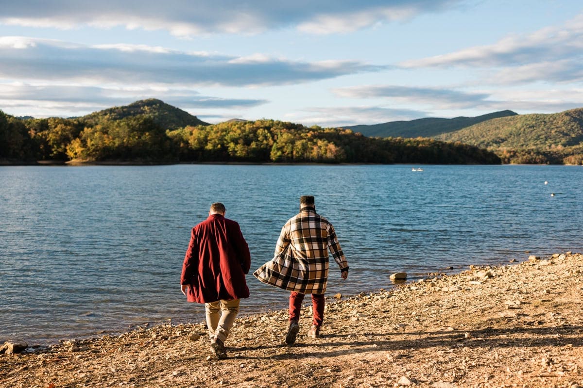 A gay couple walks along the shoreline at Carvins Cove during their engagement session